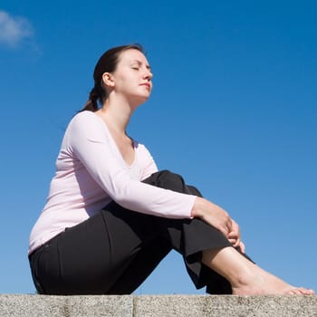 Meditation. The girl meditates with sky at background.