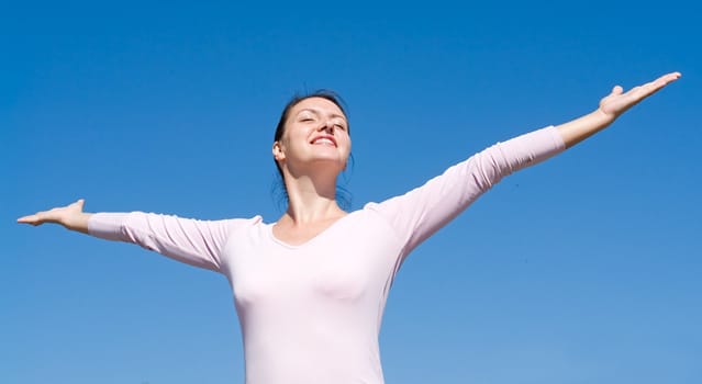 The young woman has stretched hands with sky at background 
