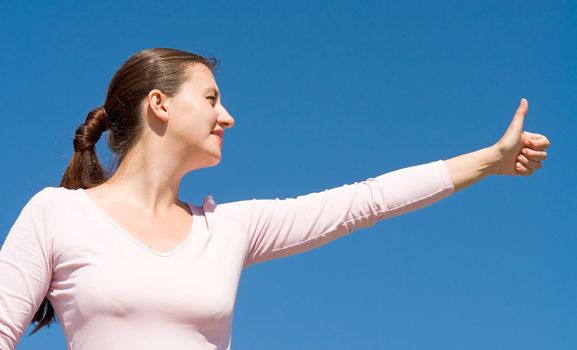 O.K. girl with thumb up on a with sky background