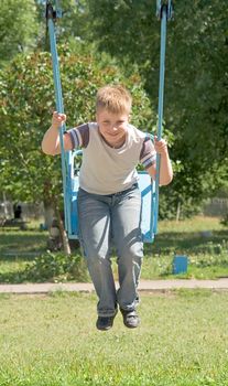 The little boy on a swing in city park