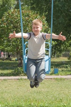 The little boy on a swing in city park