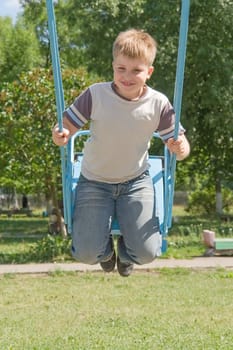 The little boy on a swing in city park