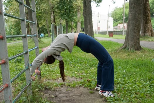 The young woman is engaged in gymnastics in city park