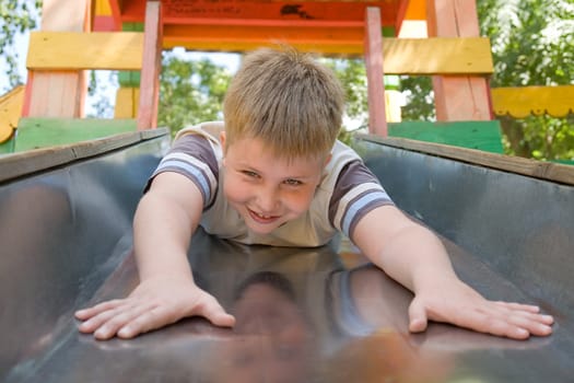 The little boy on a chute in city park