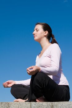 Meditation. The girl meditates with sky at background.