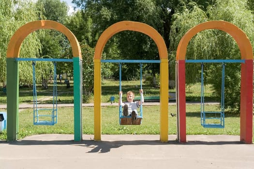 The little boy on a swing in city park