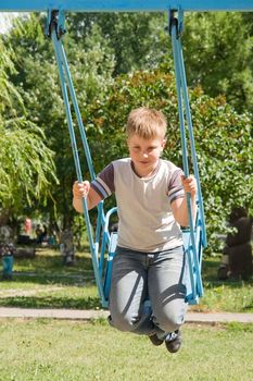 The little boy on a swing in city park