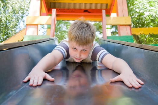 The little boy on a chute in city park