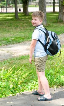 The little boy with a backpack in green park