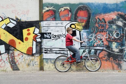 boy on a bicycle with graffiti at background