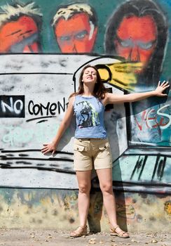 Beautiful young woman in front of grafitti covered wall.