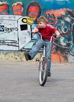 boy on a bicycle with graffiti at background