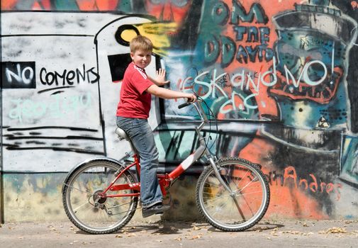 boy on a bicycle with graffiti at background