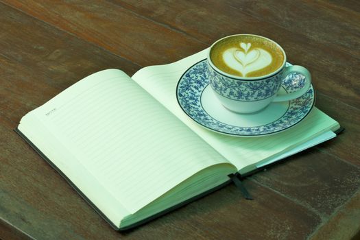 Cup of hot coffee and Notebook on wood table