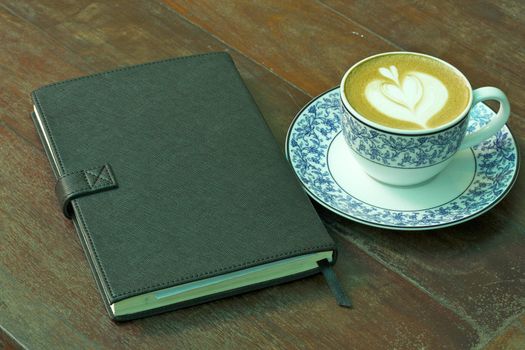 Cup of hot coffee and Notebook on wood table