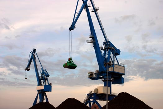 Blue cranes on the port with sunset and sand