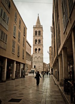 Stone paved dalmatian street in Zadar with church tower, Croatia