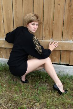 Beautiful blond female leaning against a wooden fence