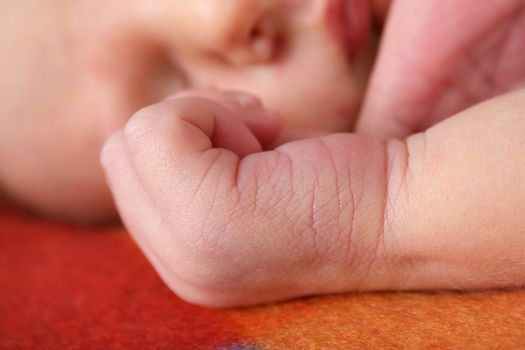 Newborn baby sleeping on a soft blanket. Focus on Hand