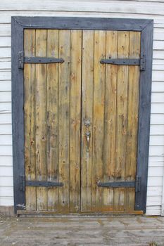 Rustic wooden door with metal hinges in doorframe