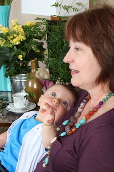 Beautiful baby boy sitting by his grandmother