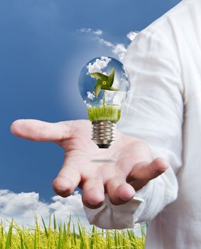 paddle , windmill and blue sky in light bulb on hand