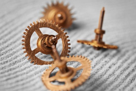 Old watch gears on the gray sand - abstract still life