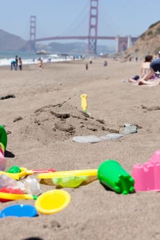 Unorganized colorful plastic beach toys on sand .