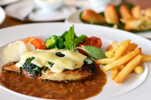 Grilled chicken steak served with chips, potatoes and vegetables