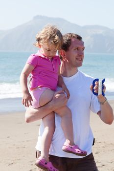 Father and daughter flying kite on the beach on sunny day.