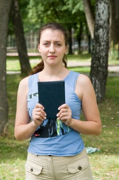 Beautiful young woman with book in park