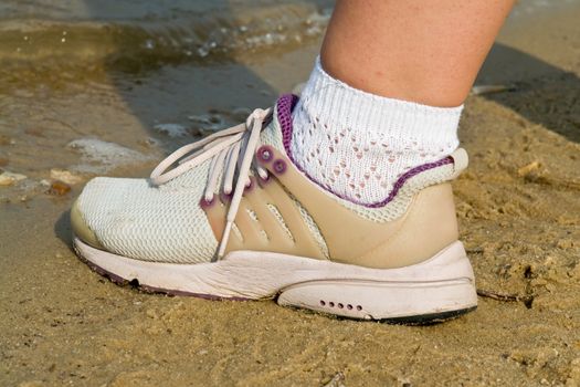 foot in running shoes at sandy coast