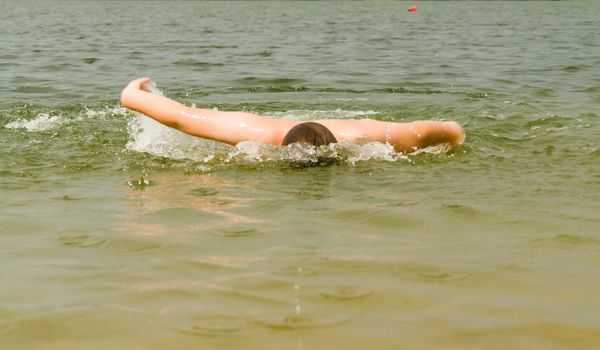 the little boy quickly swims the butterfly stroke