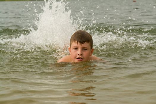 the little boy swims. splashes on a background