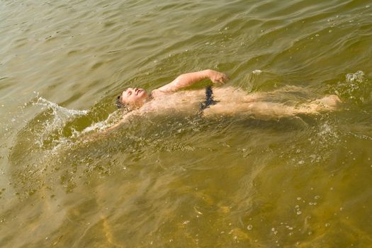the little boy quickly swims on a back