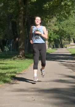The sports girl runs in a park