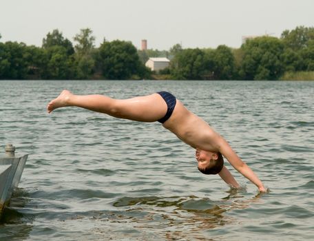The little boy jumps from a pier in water