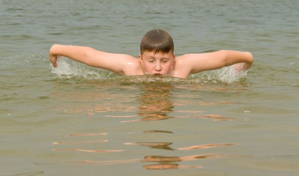 the little boy quickly swims the butterfly stroke