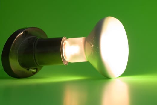 Glowing light bulb on a green background
