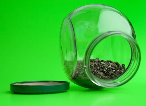 Green tea in glass jar on a green background.