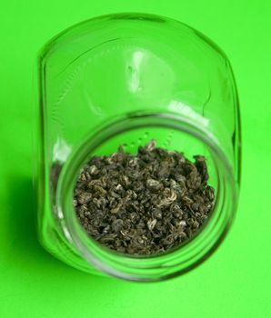 Green tea in glass jar on a green background.