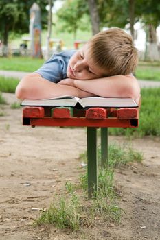 schoolboy sleeps on a bench in park