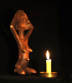 African Wooden Figure, Praying Before the 
Candle in the Dark.