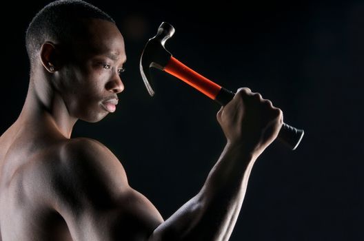 Young african american showing his muscles and ready to work with hammer.