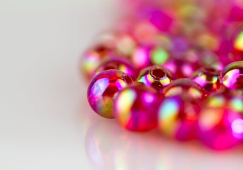 red beads with colorful light reflection on white surface