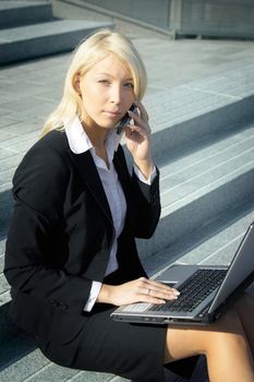 Young businesswoman using laptop computer in city, sitting on stairway