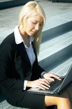 Young businesswoman using laptop computer in city, sitting on stairway