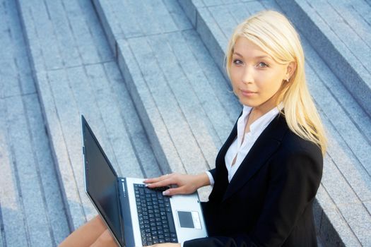 Businesswoman working with laptop computer, looking at camera