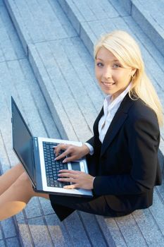 Businesswoman working with laptop computer, looking at camera