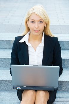 Businesswoman working with laptop computer, looking at camera
